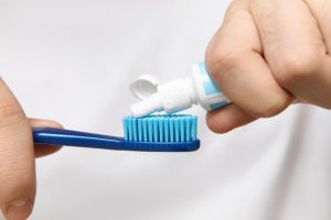 Osoba sipa pastu za zube na plavu četkicu za zube