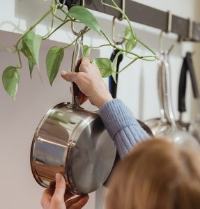 The woman hangs the pan on the kitchen hook